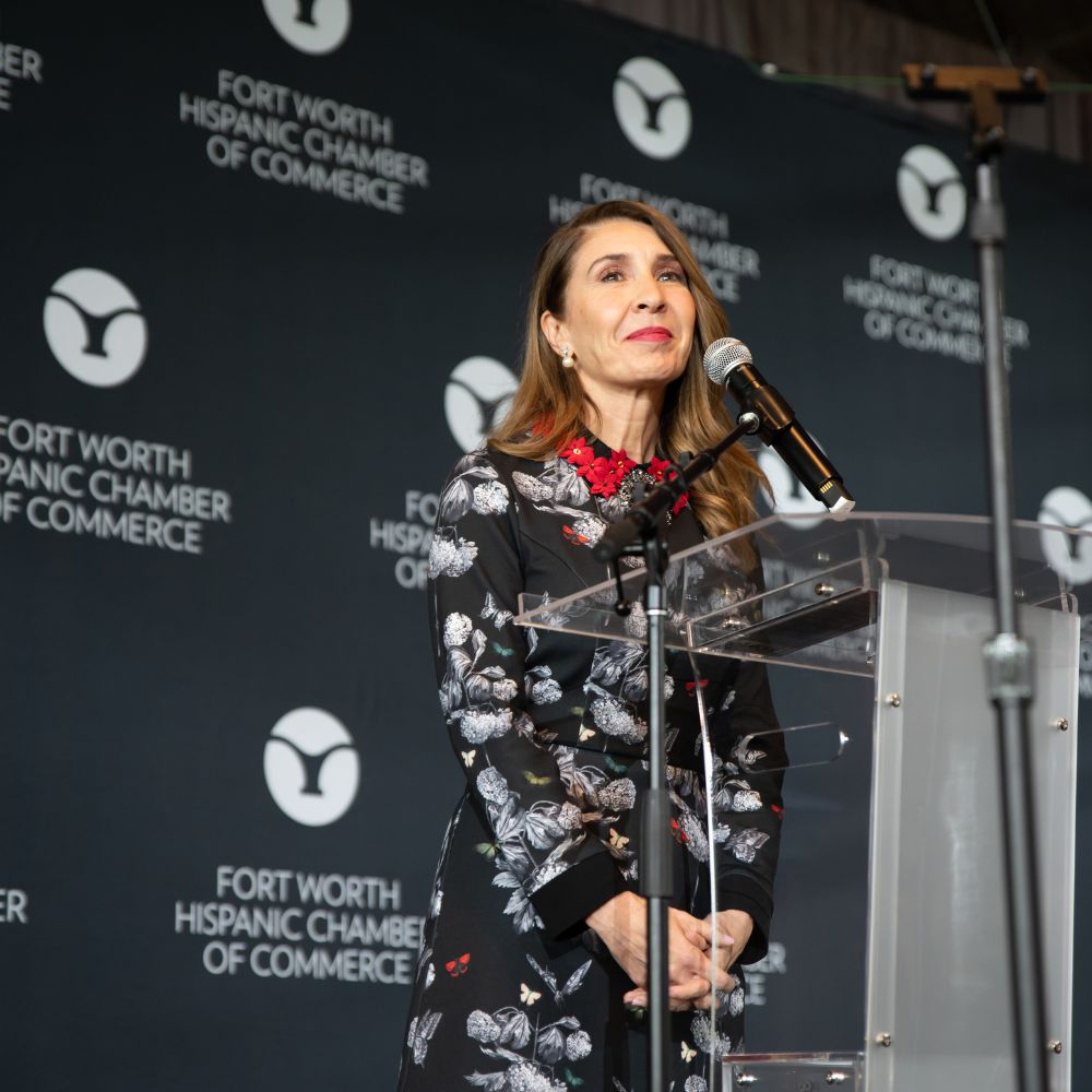 Woman speaking at podium with backdrop logos