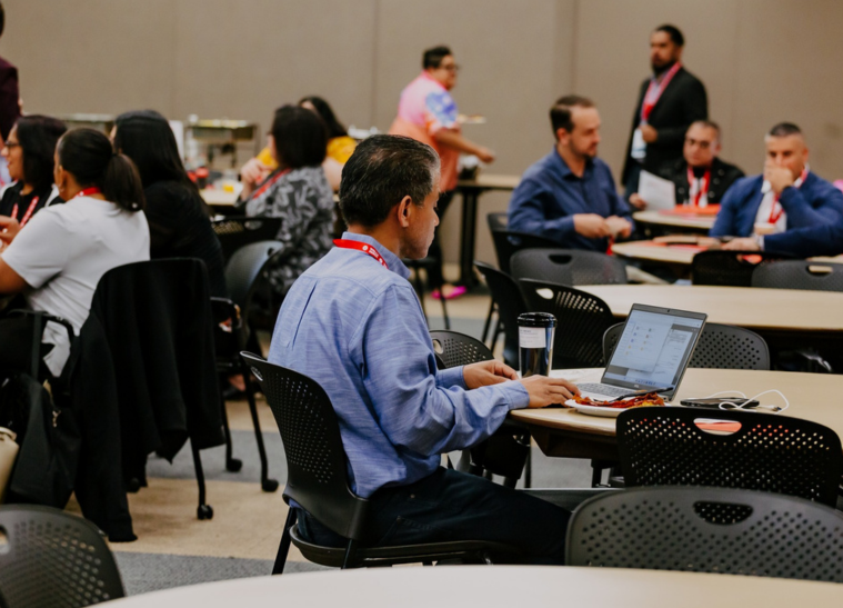 Conference attendees using laptops at round tables