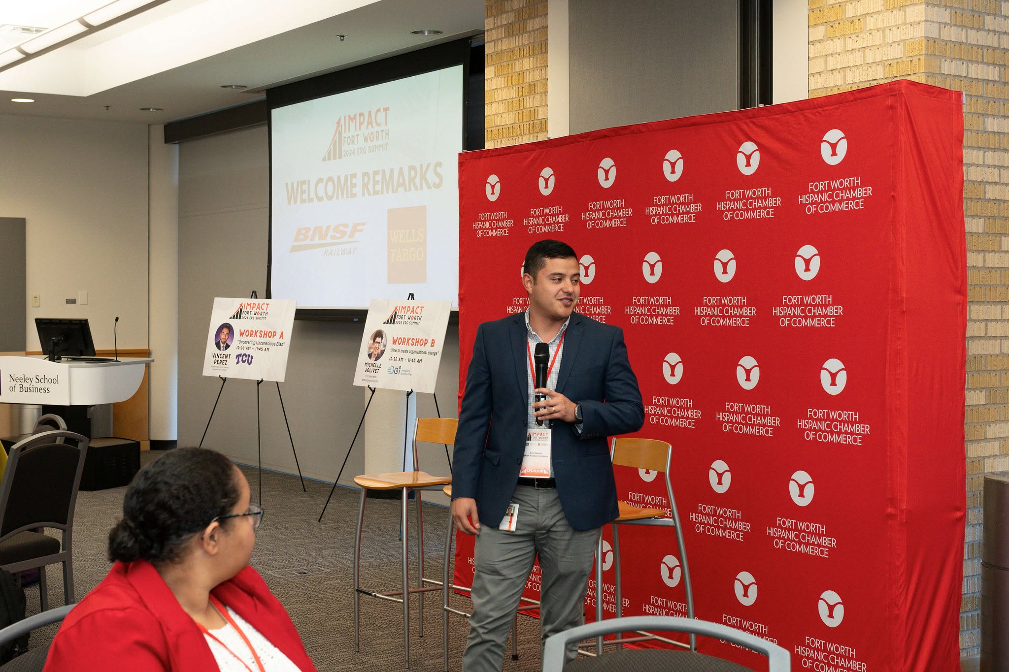 Man speaking at business event with red backdrop
