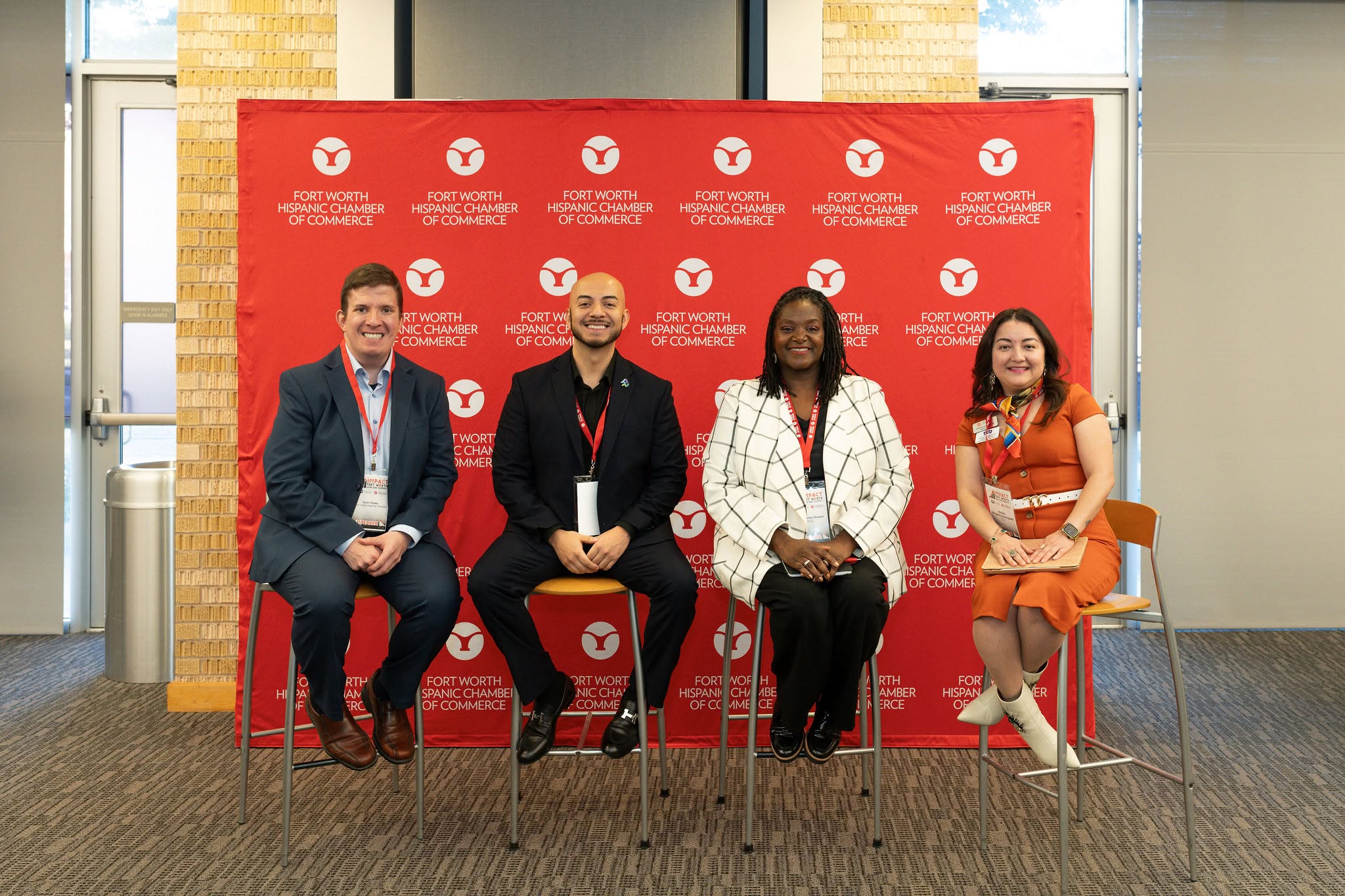 Four panelists seated in front of red backdrop