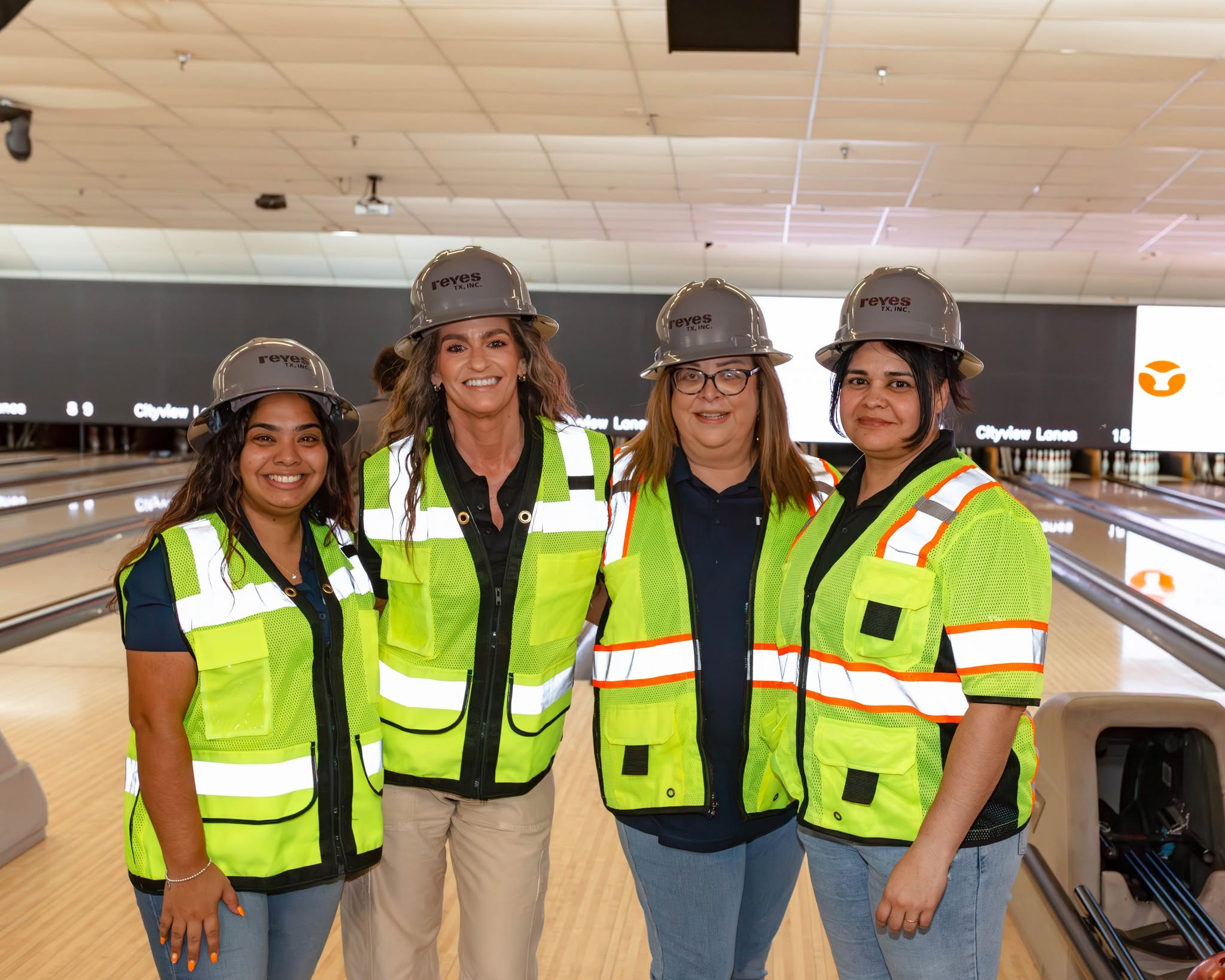 Four people in hard hats at bowling alley