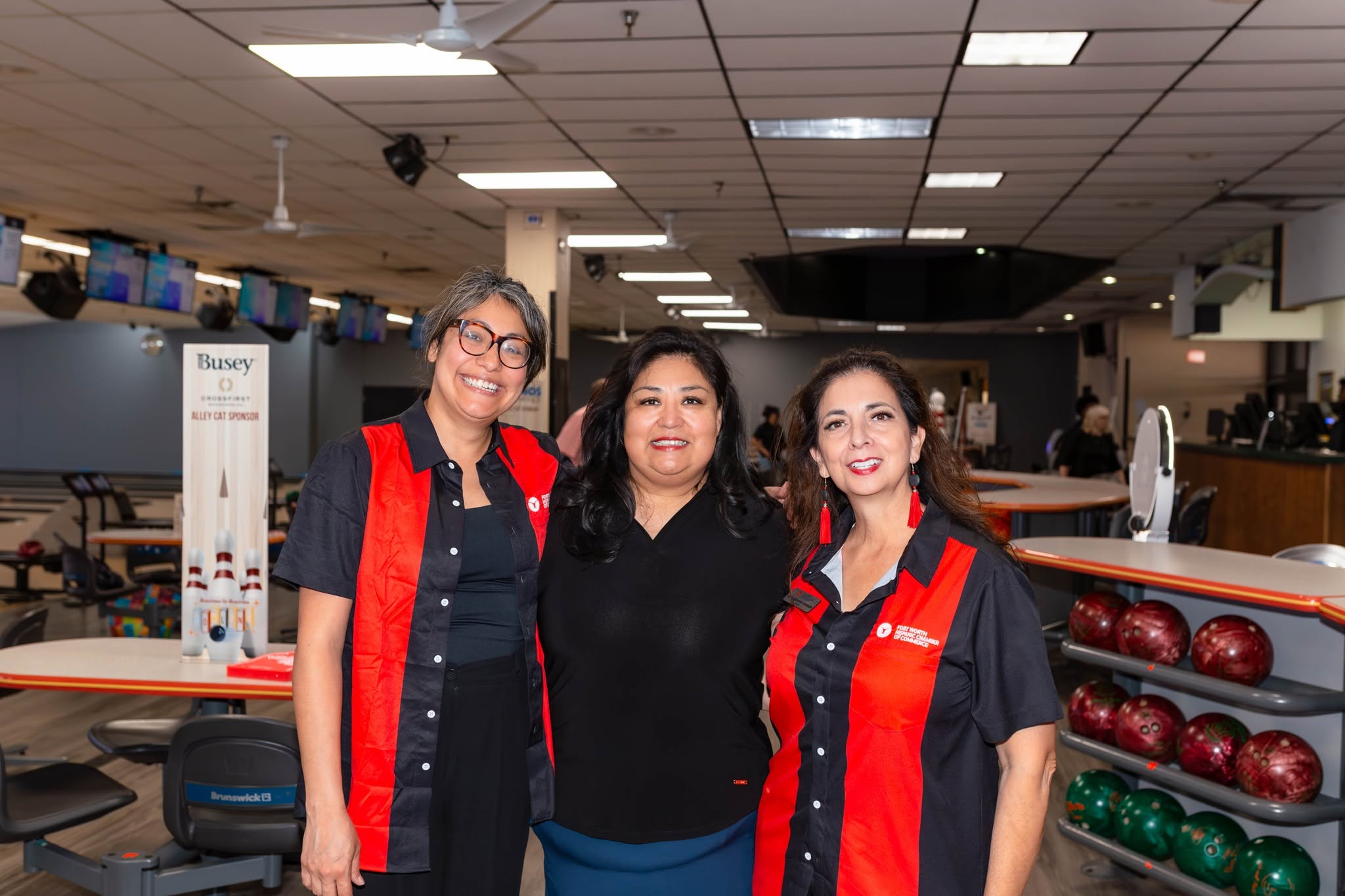 Three women smiling in bowling alley