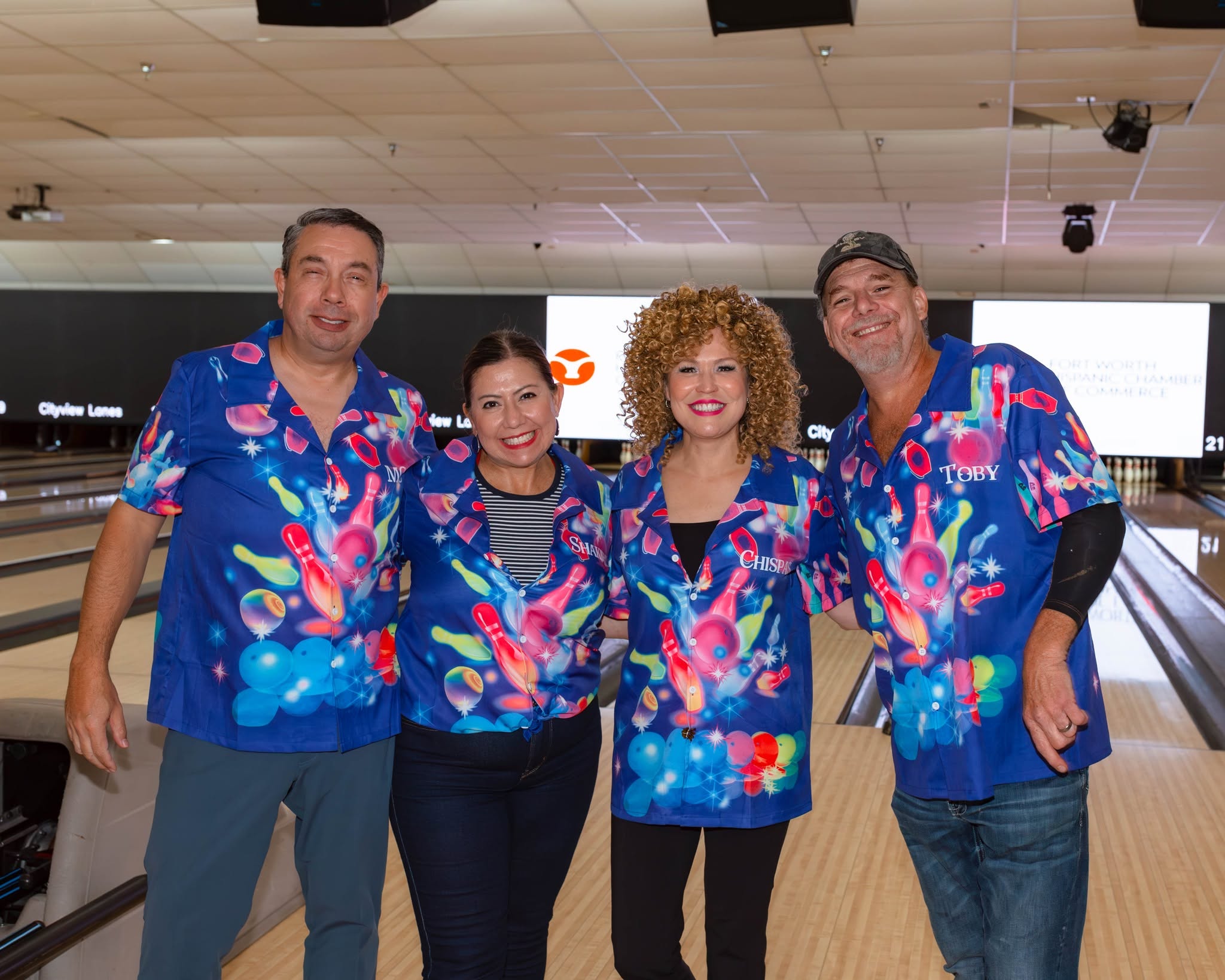 Four smiling bowlers in matching colorful shirts