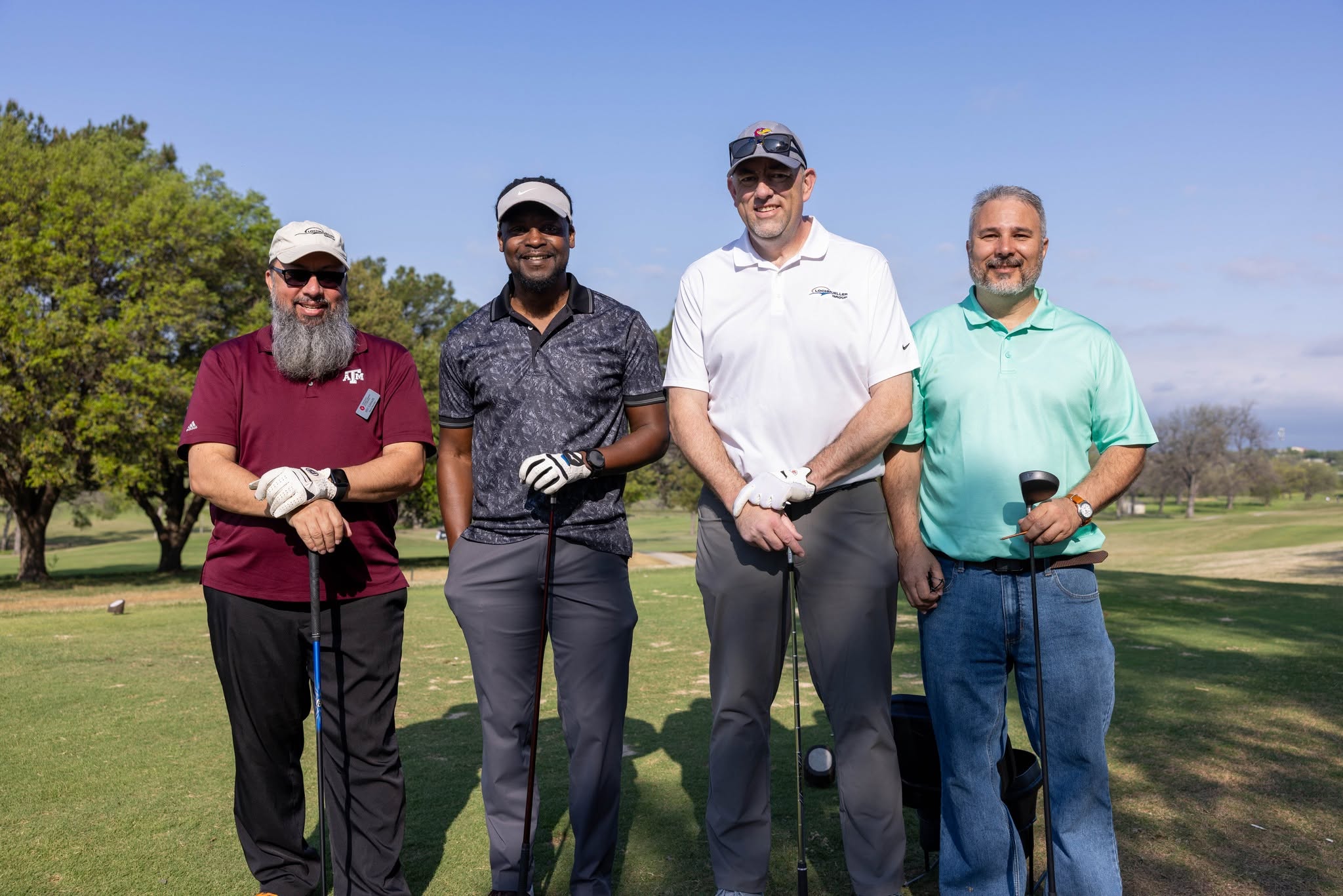Four golfers posing on sunny golf course