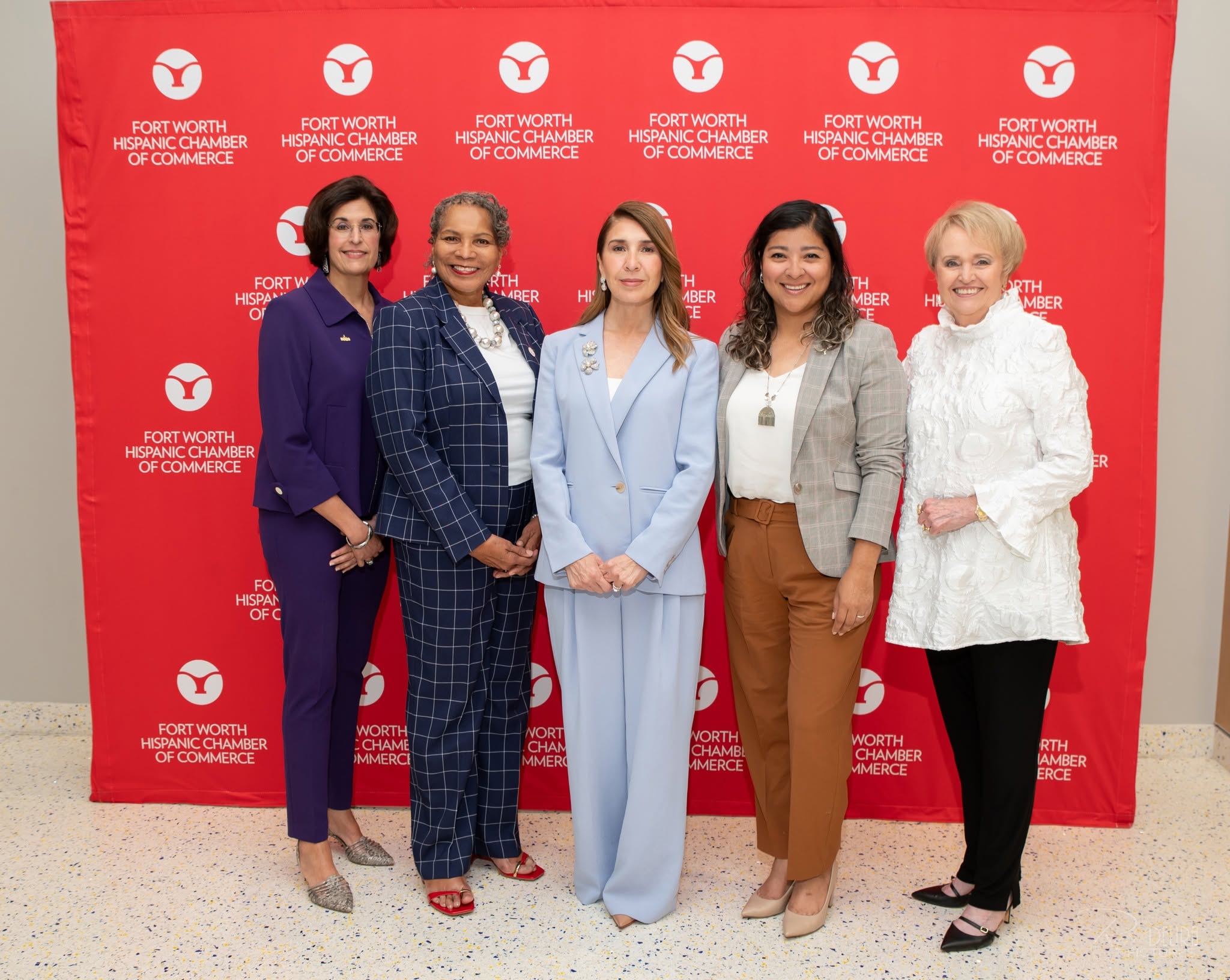 Five women posing in front of red backdrop