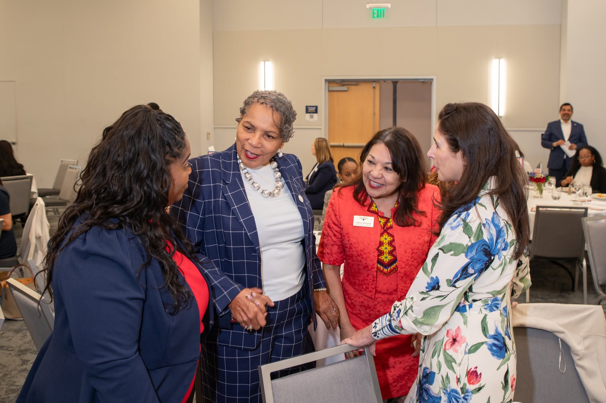 Four women conversing at conference table