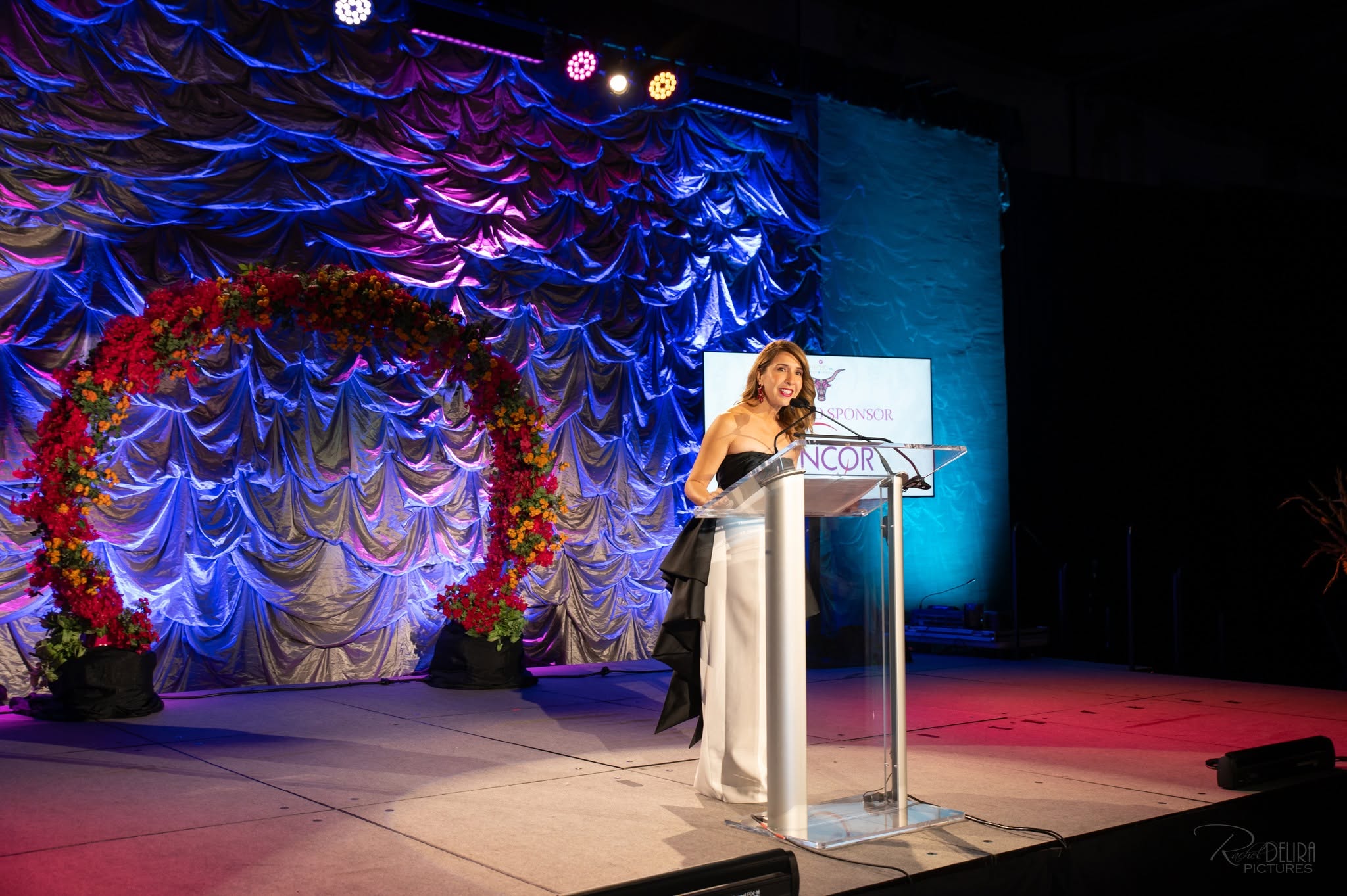 Woman presenter at gala podium with floral arch