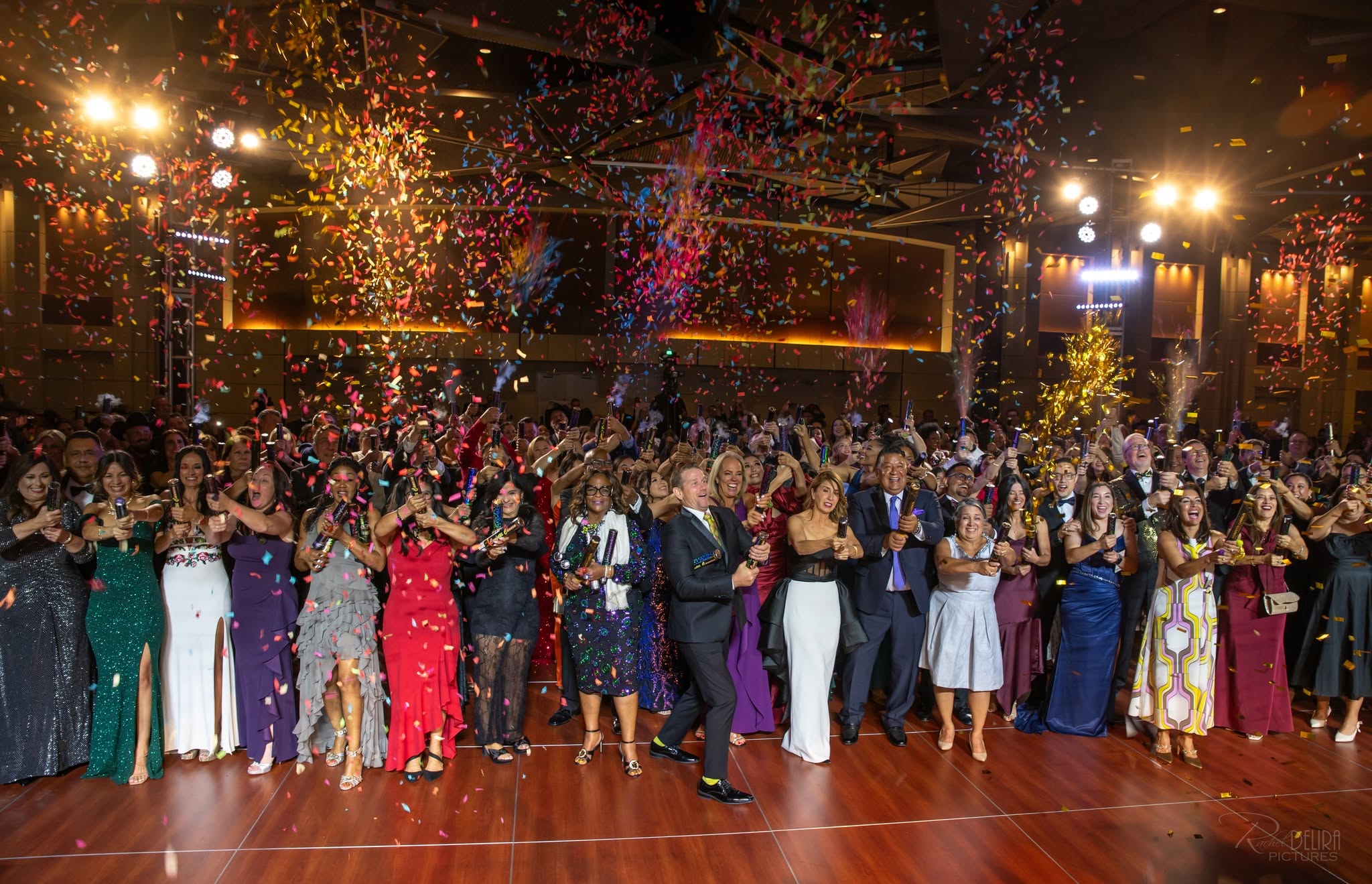 Crowd in formal attire celebrating under confetti