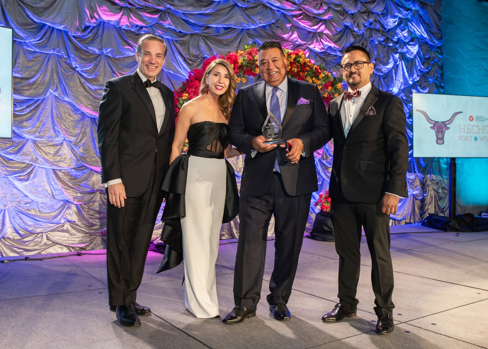 Four people in formalwear holding award onstage